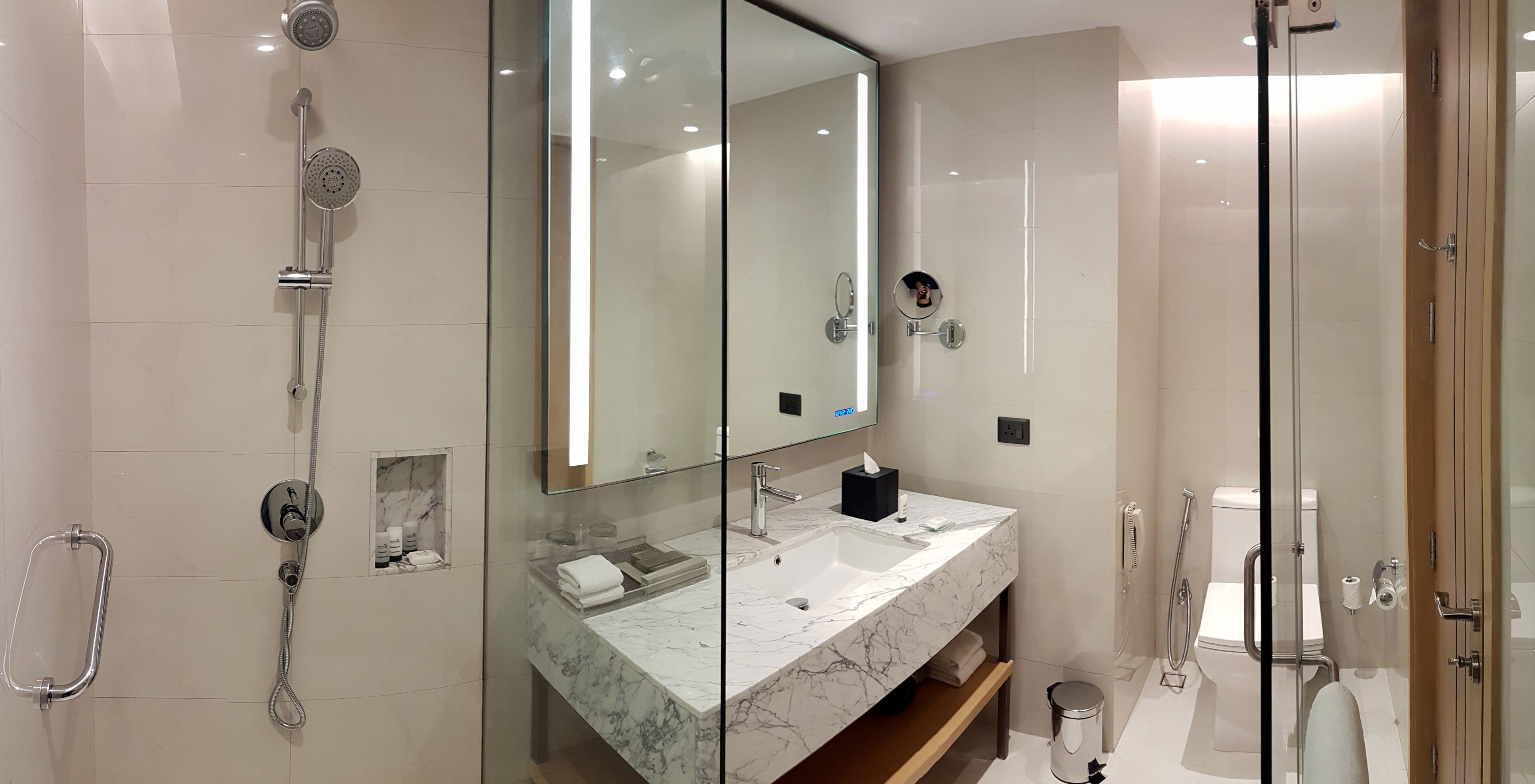A modern bathroom with a glass shower enclosure, a marble sink, and a large mirror.