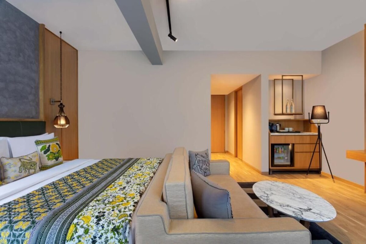A modern hotel room with a bed, sofa, and dining table.