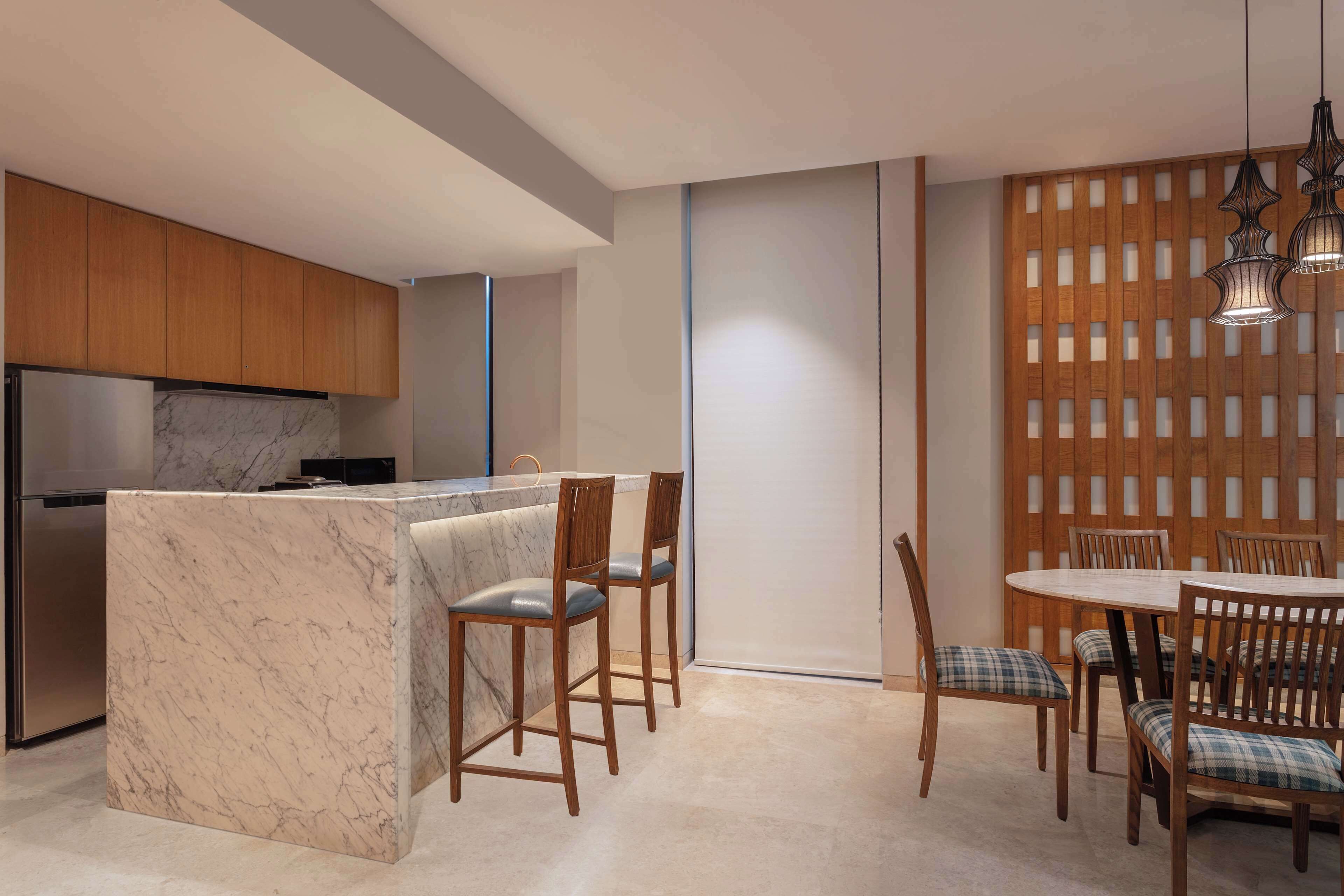 A modern kitchen with marble countertops, wooden cabinets, and a dining area with a wooden table and chairs.