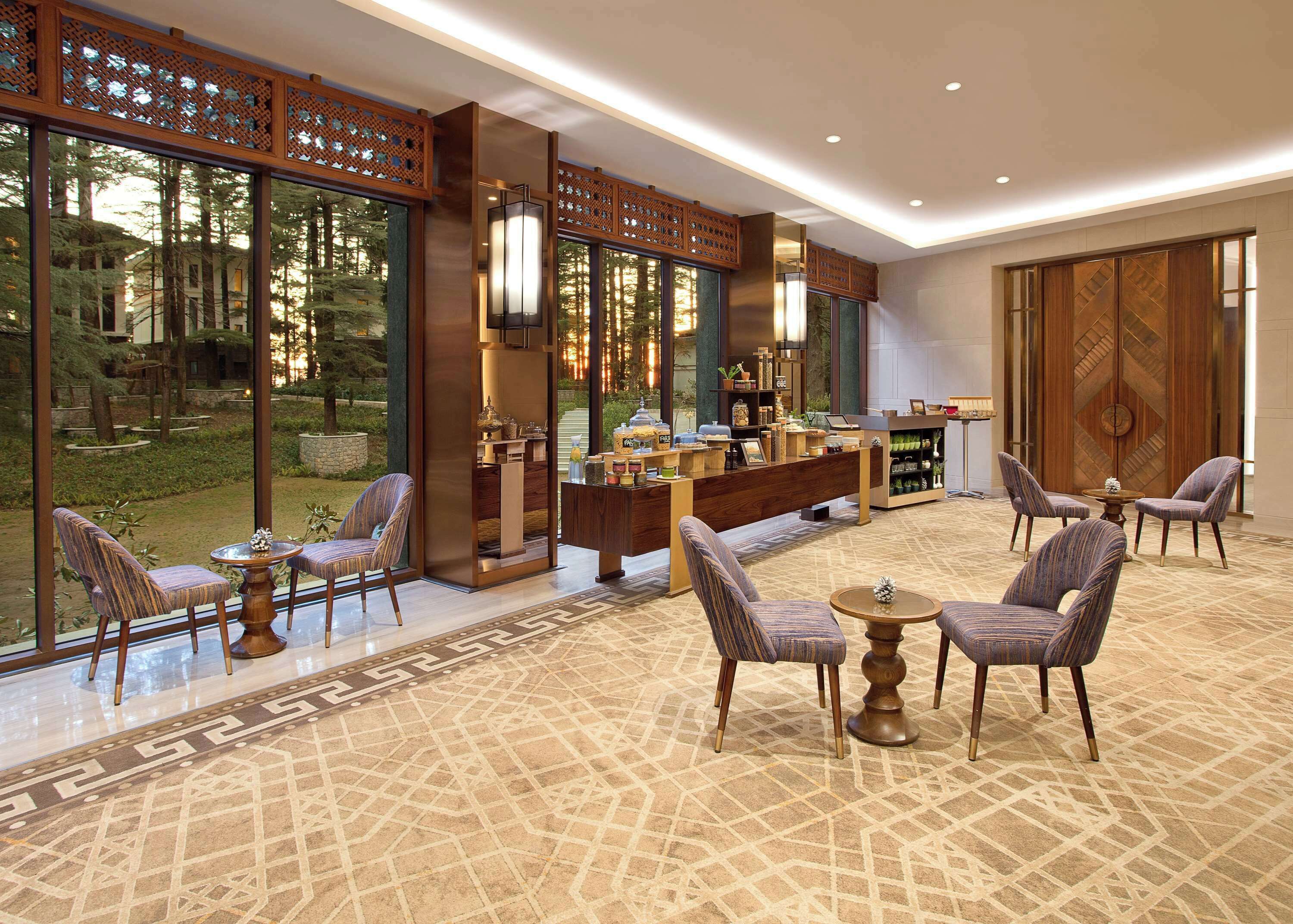 A modern hotel lobby with large windows, a reception desk, and seating areas.