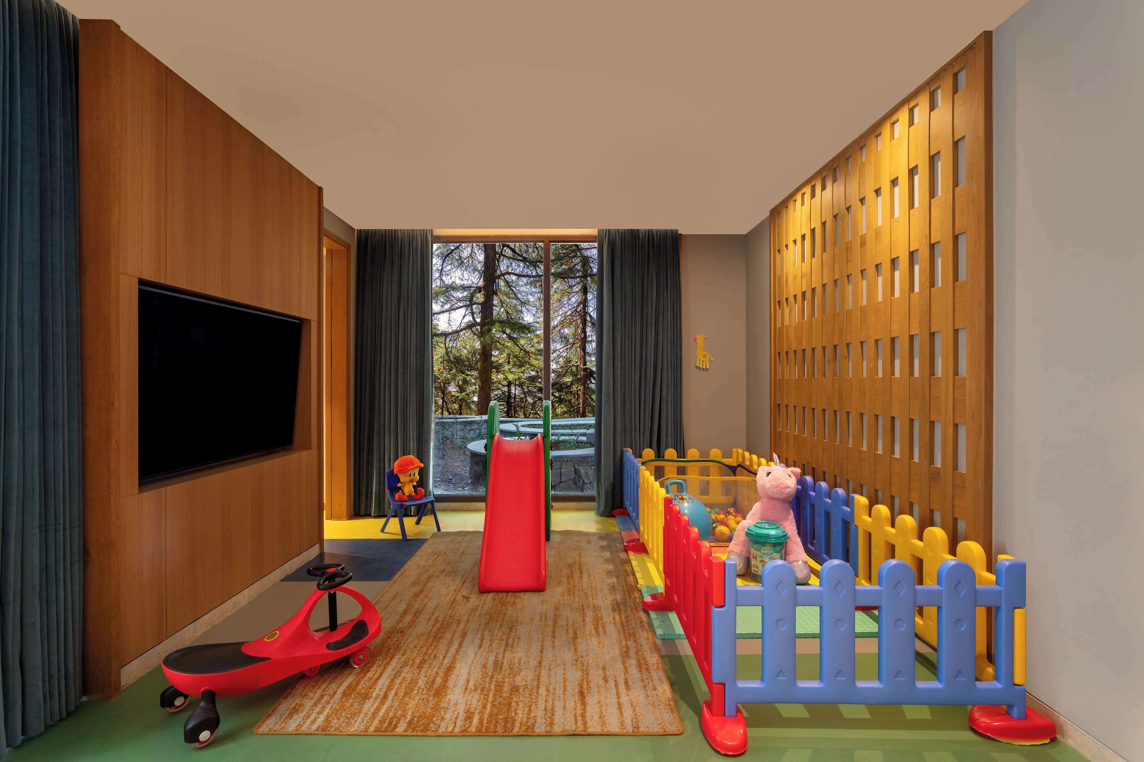 Zona de juegos infantiles con tobogán, patinete y corralito con juguetes.