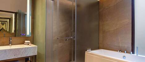A modern bathroom with a glass-enclosed shower, a marble sink, and a large bathtub.