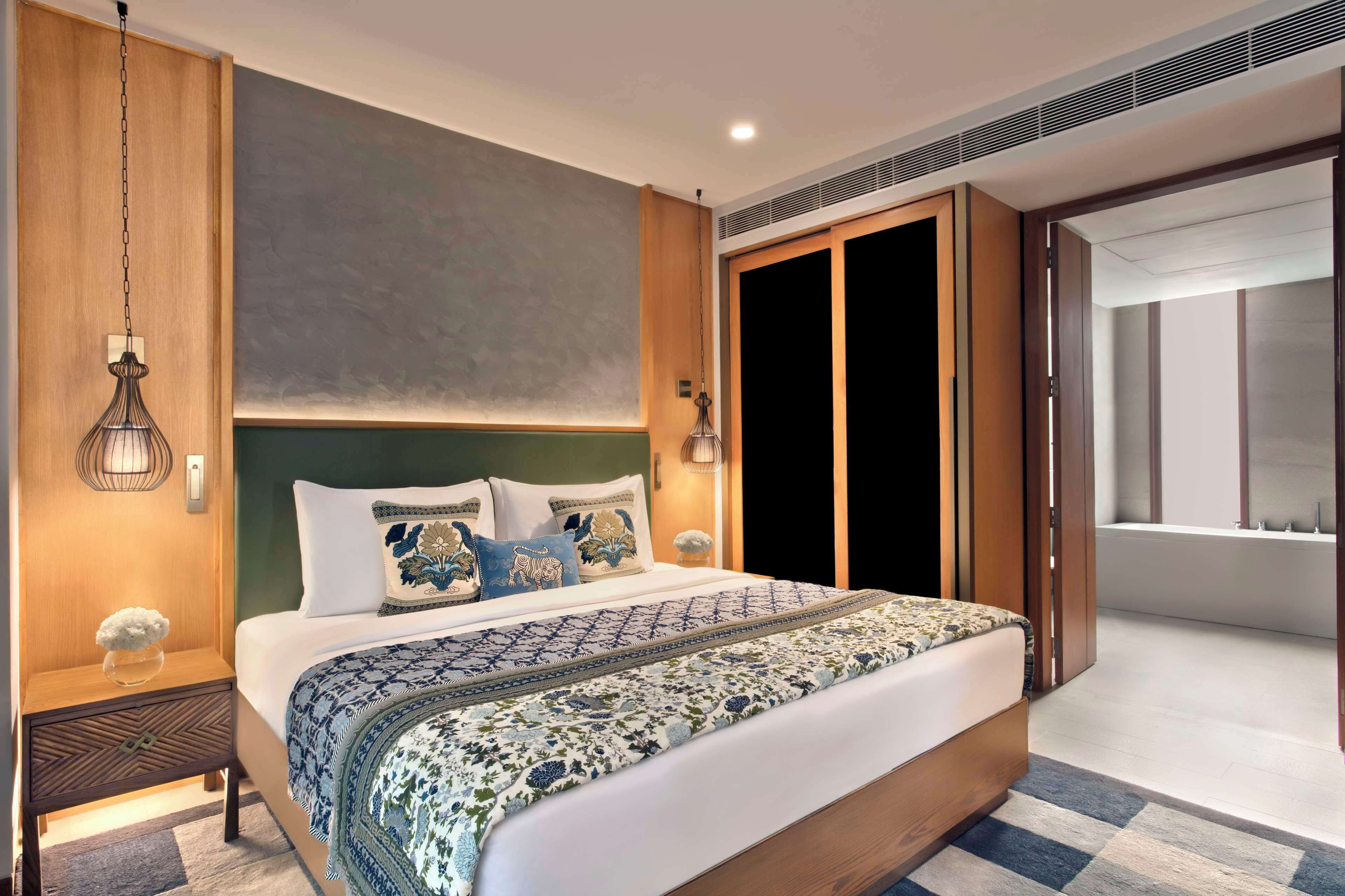 A modern bedroom with a large bed, wooden headboard, and a view of a balcony.