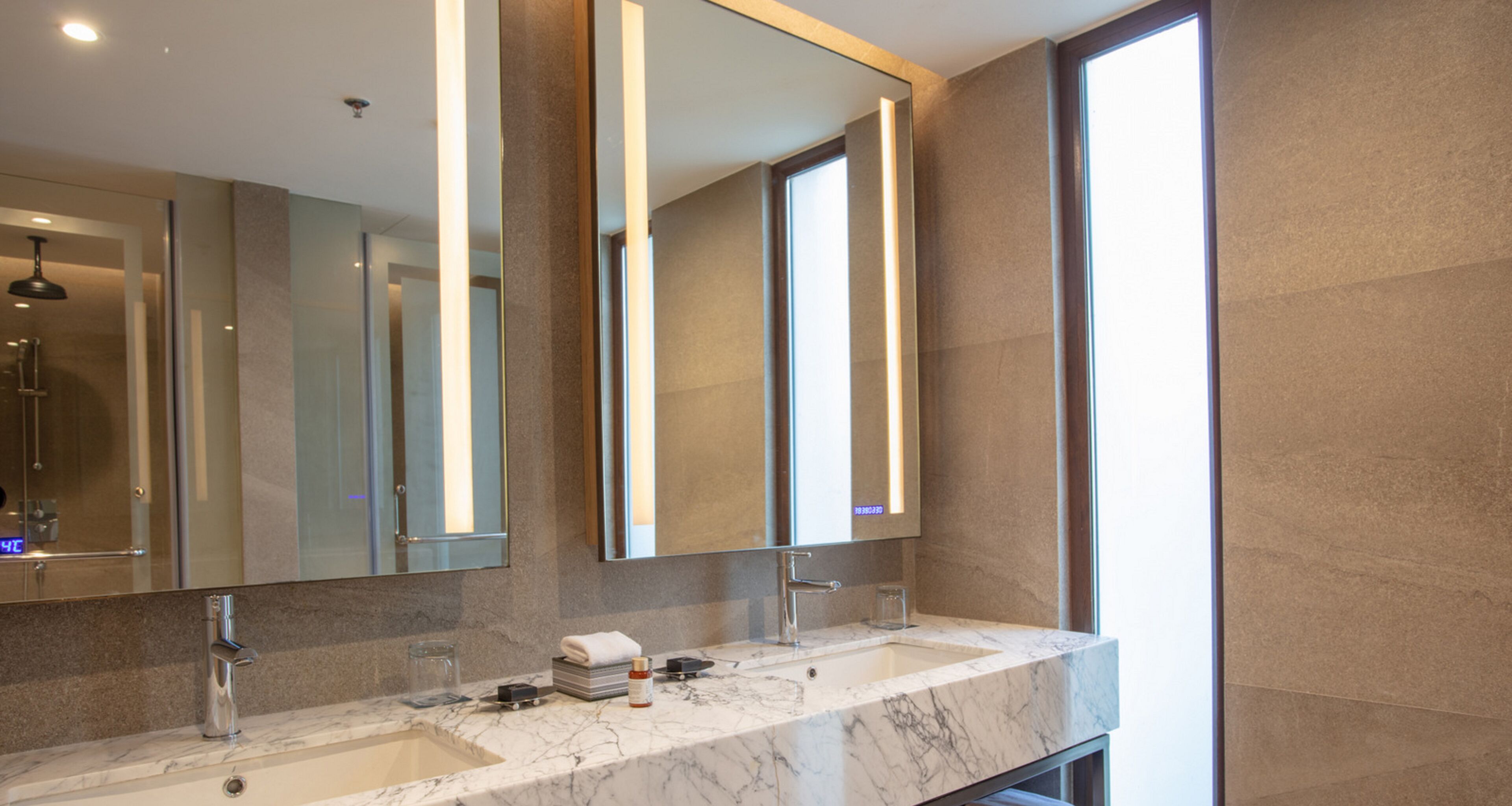 A modern bathroom with two sinks, a large mirror, and a glass shower enclosure.