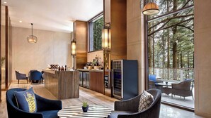 A modern kitchen with a bar area, large windows, and a balcony with outdoor seating. - Hyatt Regency Dharamshala Resort (Dharamshala)