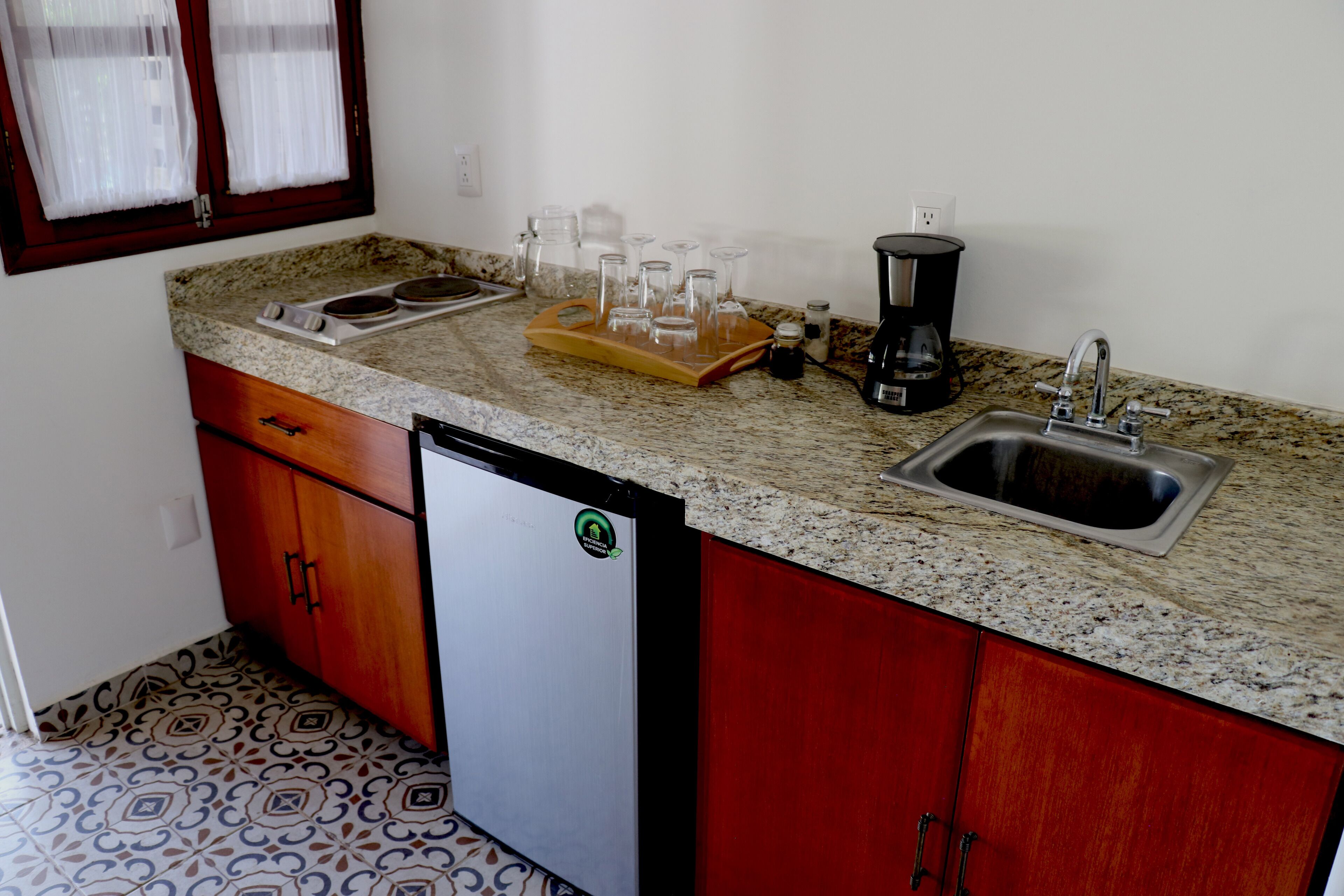 A kitchen with granite countertops, a sink, a coffee maker, and a refrigerator.