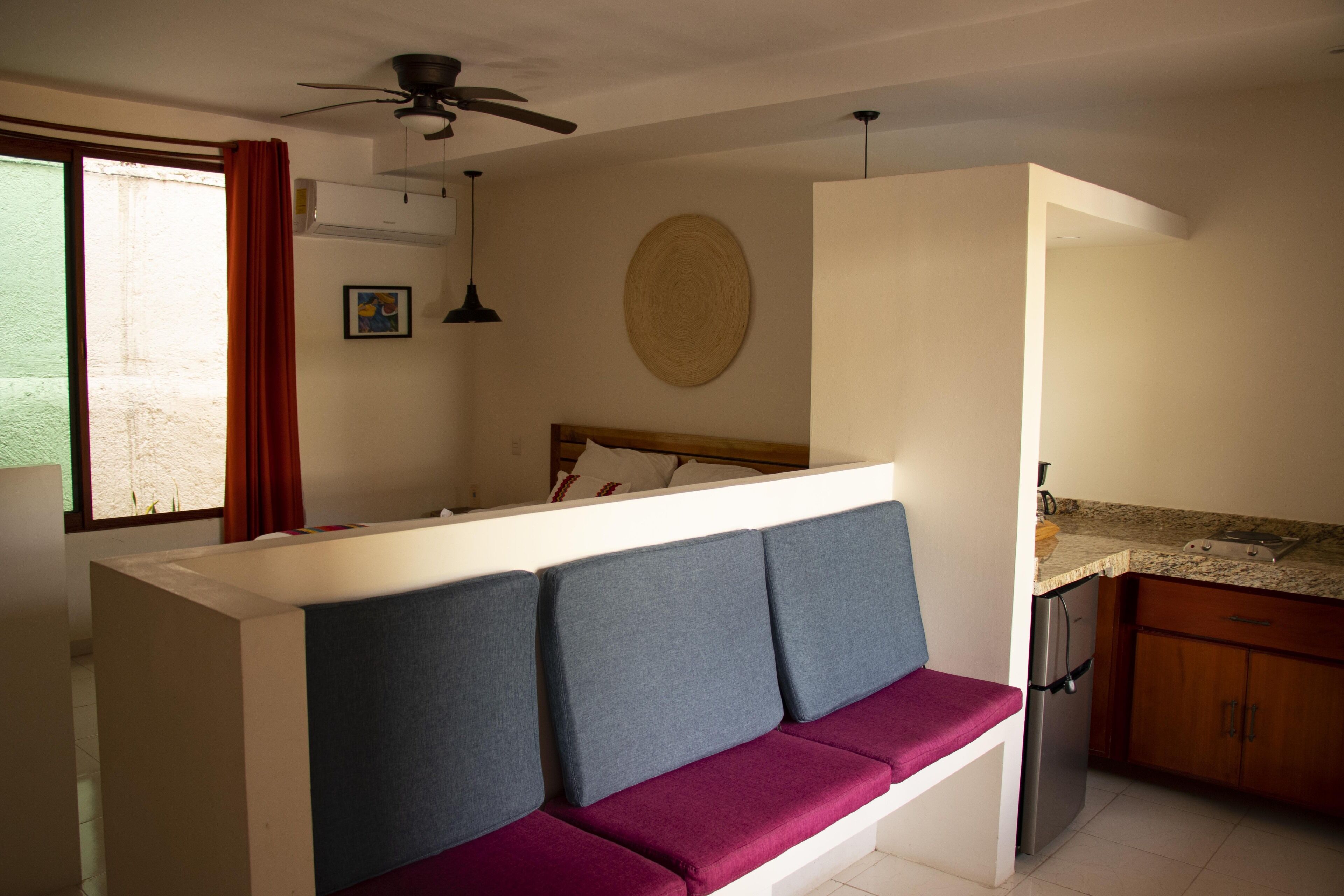 A compact kitchen with a built-in refrigerator, a wooden countertop, and a window with a curtain.