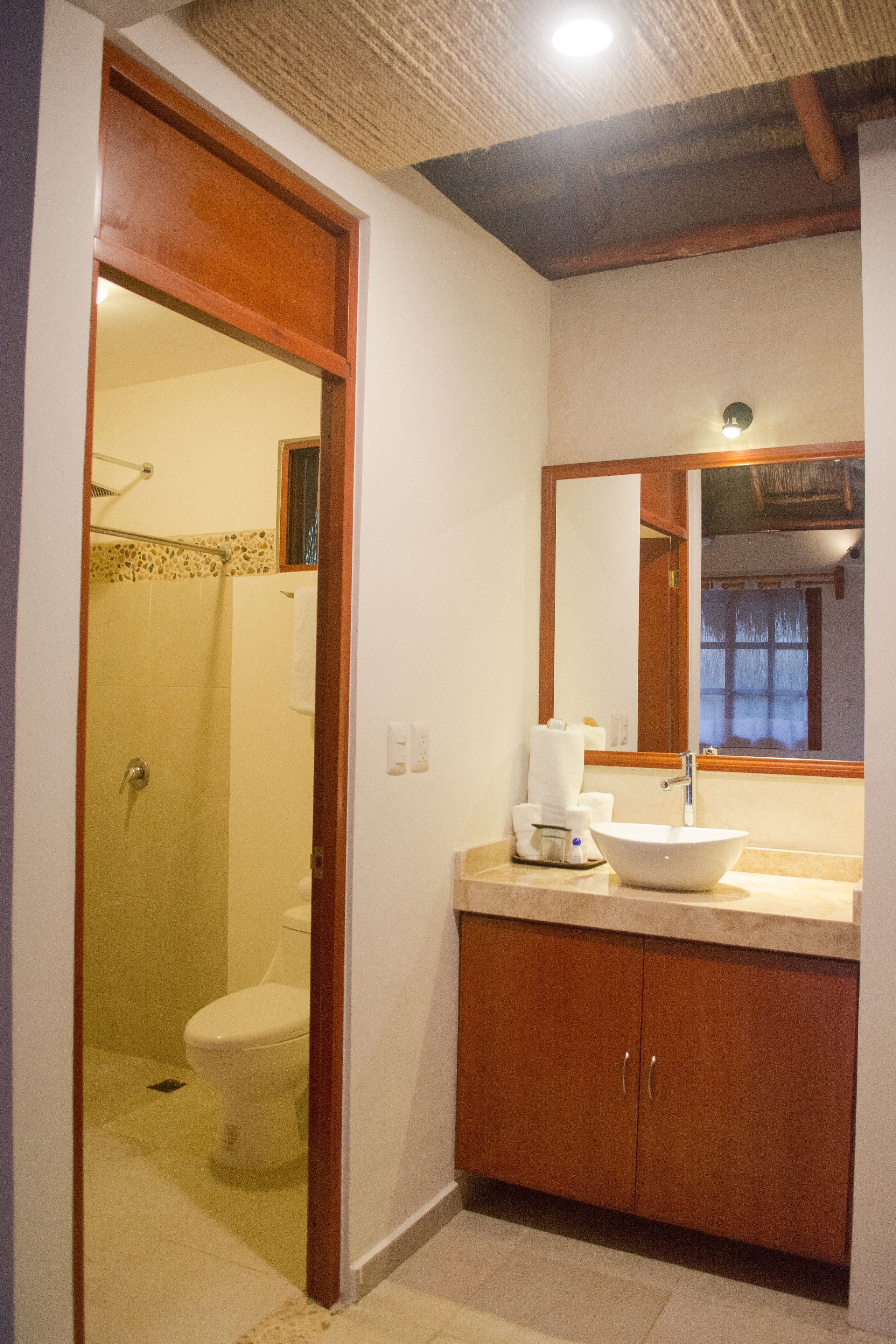 Ein Badezimmer mit Dusche, Toilette, Waschbecken und Spiegel.