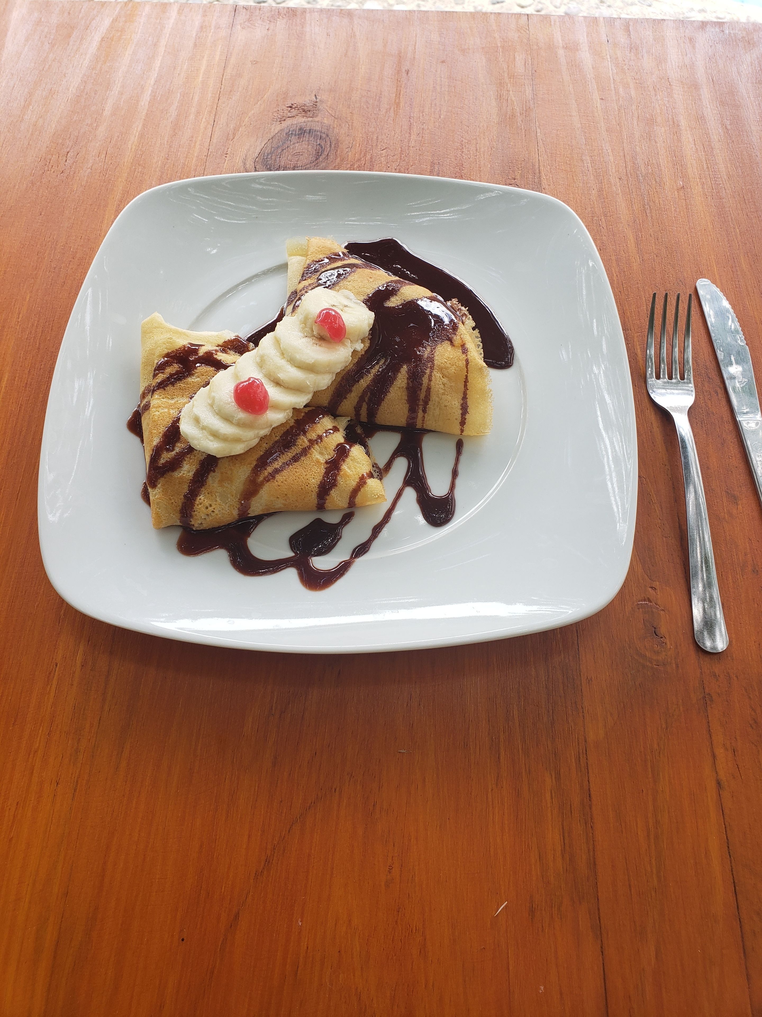 Un plato de crepas con crema batida y salsa de chocolate.