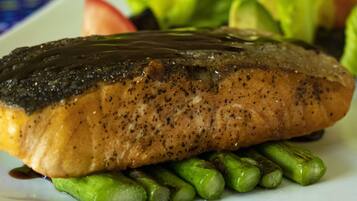 Un plato con un trozo de salmón cubierto con salsa oscura, servido sobre una cama de espárragos.