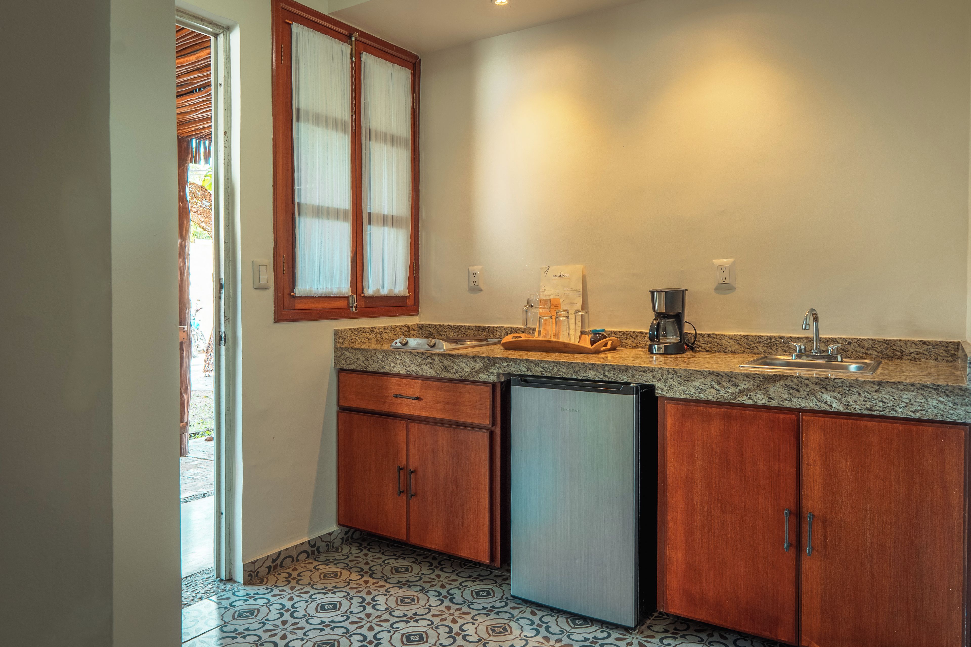 Una cocina con armarios de madera, lavavajillas integrado, cafetera y un lavabo.