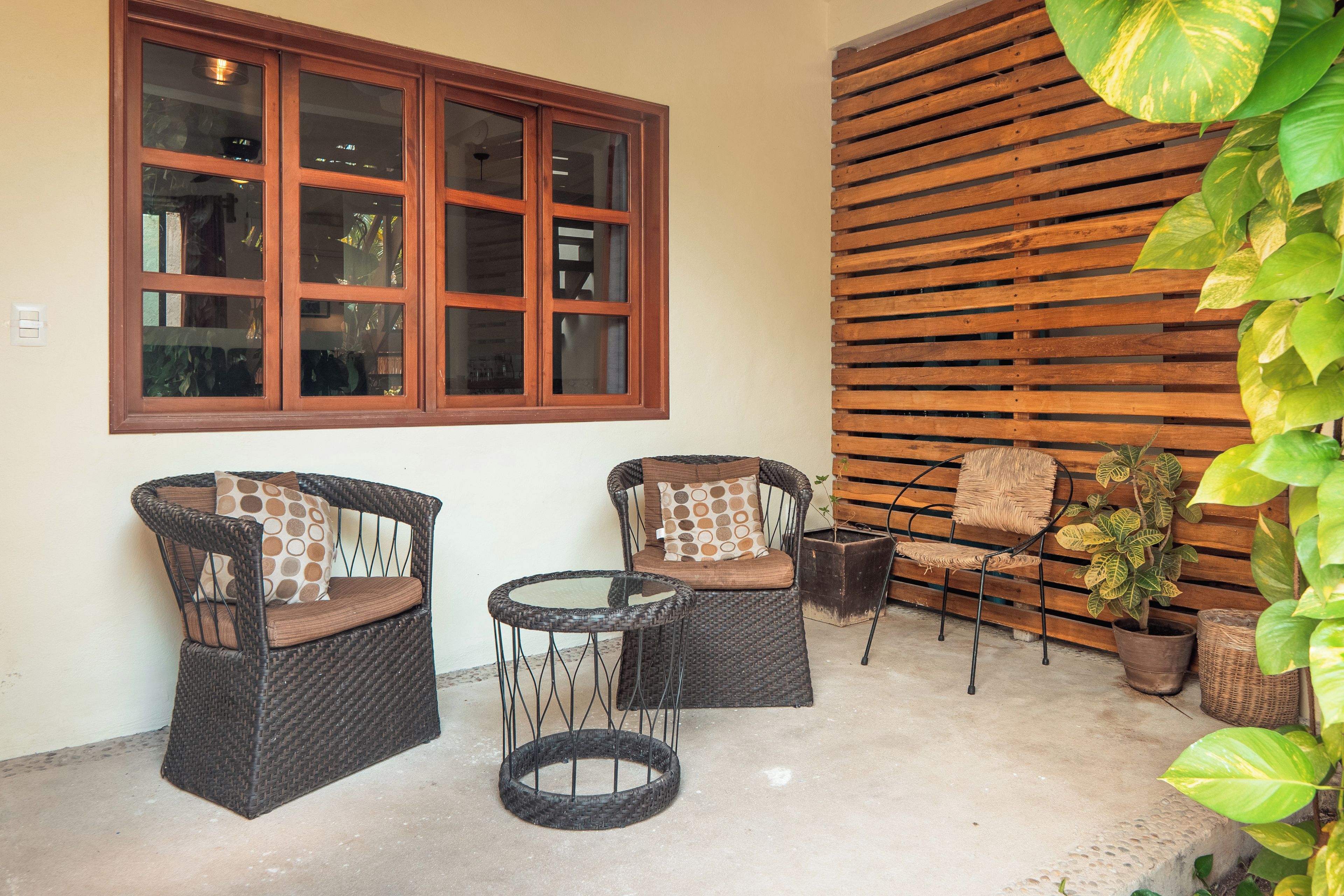 Un patio con mobiliario de mimbre, una mesa redonda y una pared de madera.