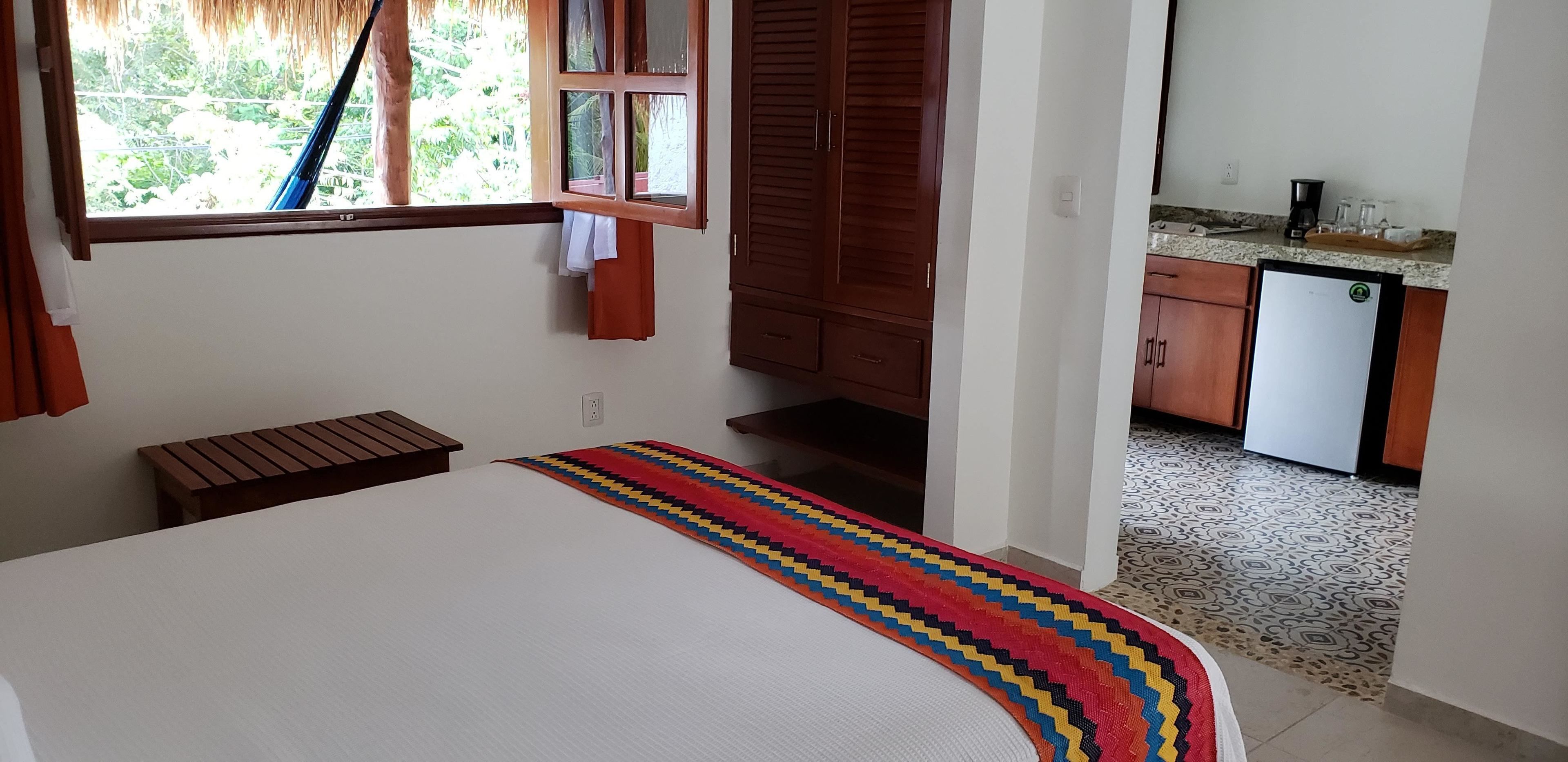 Un dormitorio con cama, ventana, armario y kitchenette.