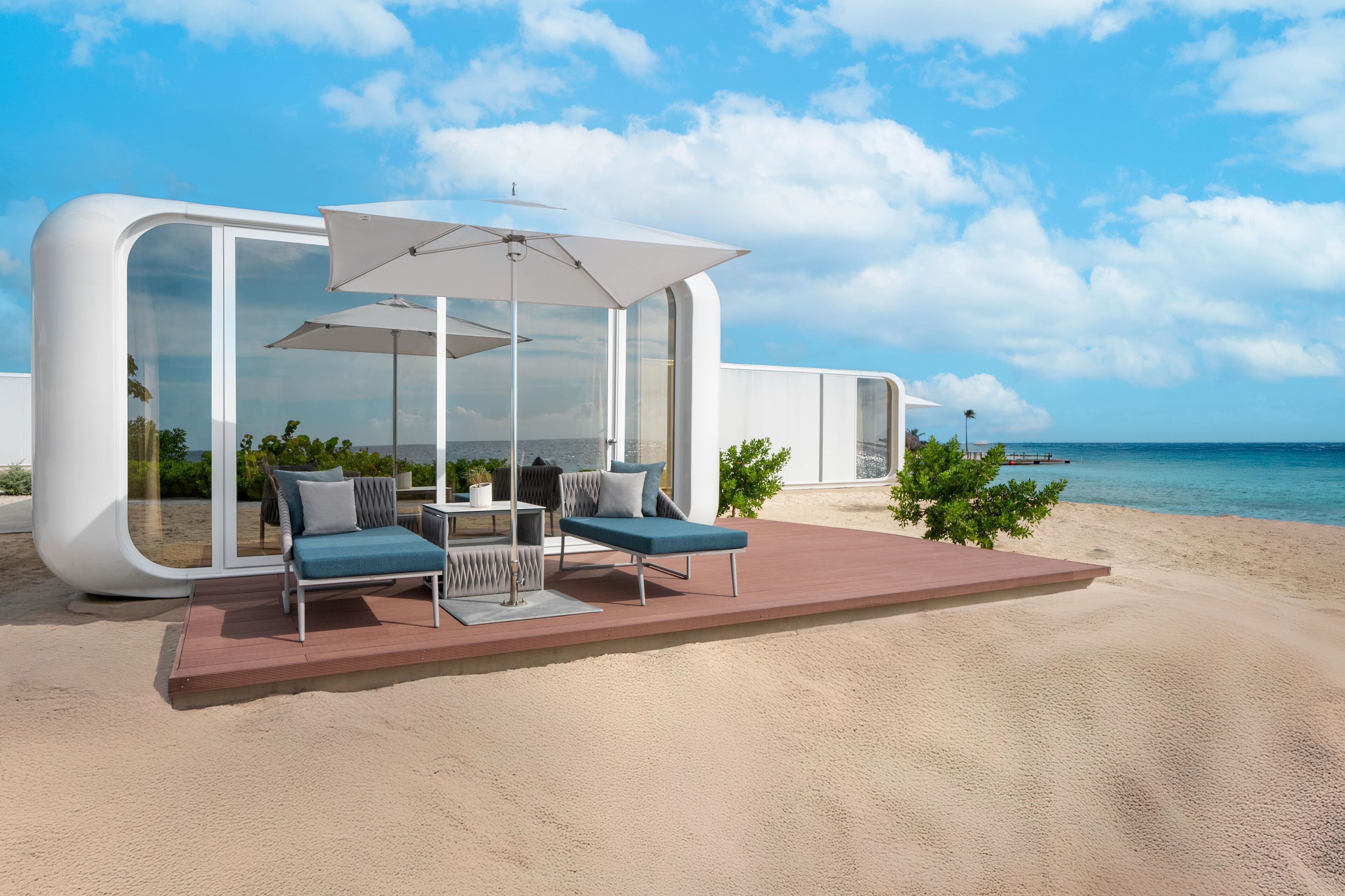 A modern beachside lounge with glass walls, outdoor seating, and a view of the ocean.