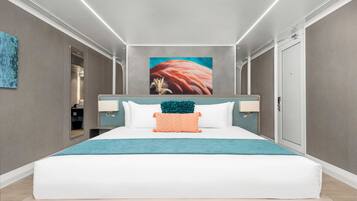 A modern hotel room with a large bed, a teal throw blanket, and a large painting on the wall.