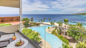 Un balcone con vista diretta su una piscina, palme e l'oceano.