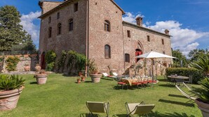A large brick building with a courtyard featuring outdoor seating and potted plants.