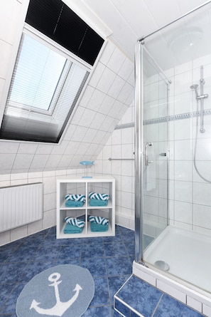 Ein modernes Badezimmer mit Duschkabine aus Glas, einem Oberlicht und blau gefliestem Boden.