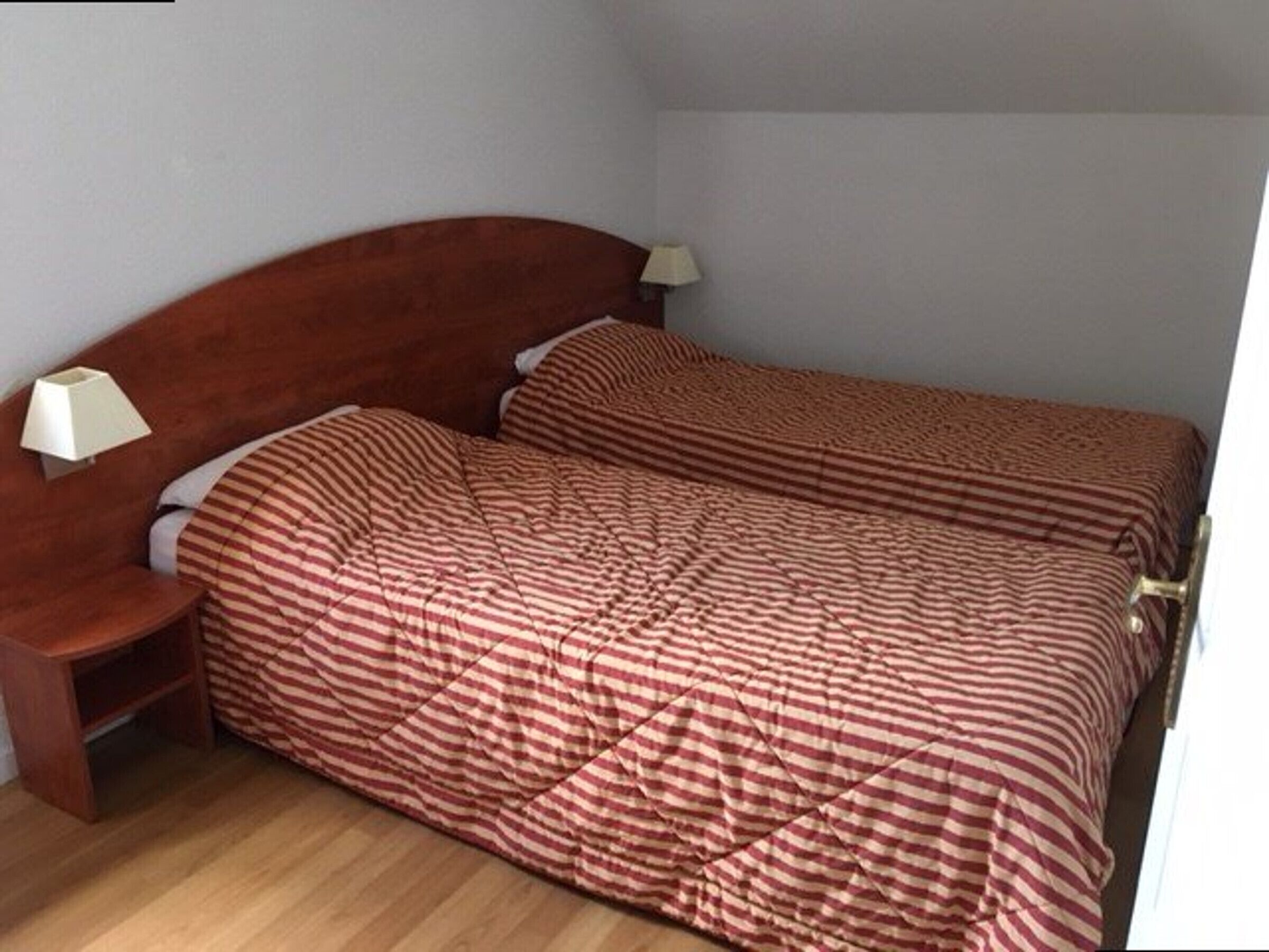 A single bed with a wooden headboard and two bedside lamps.