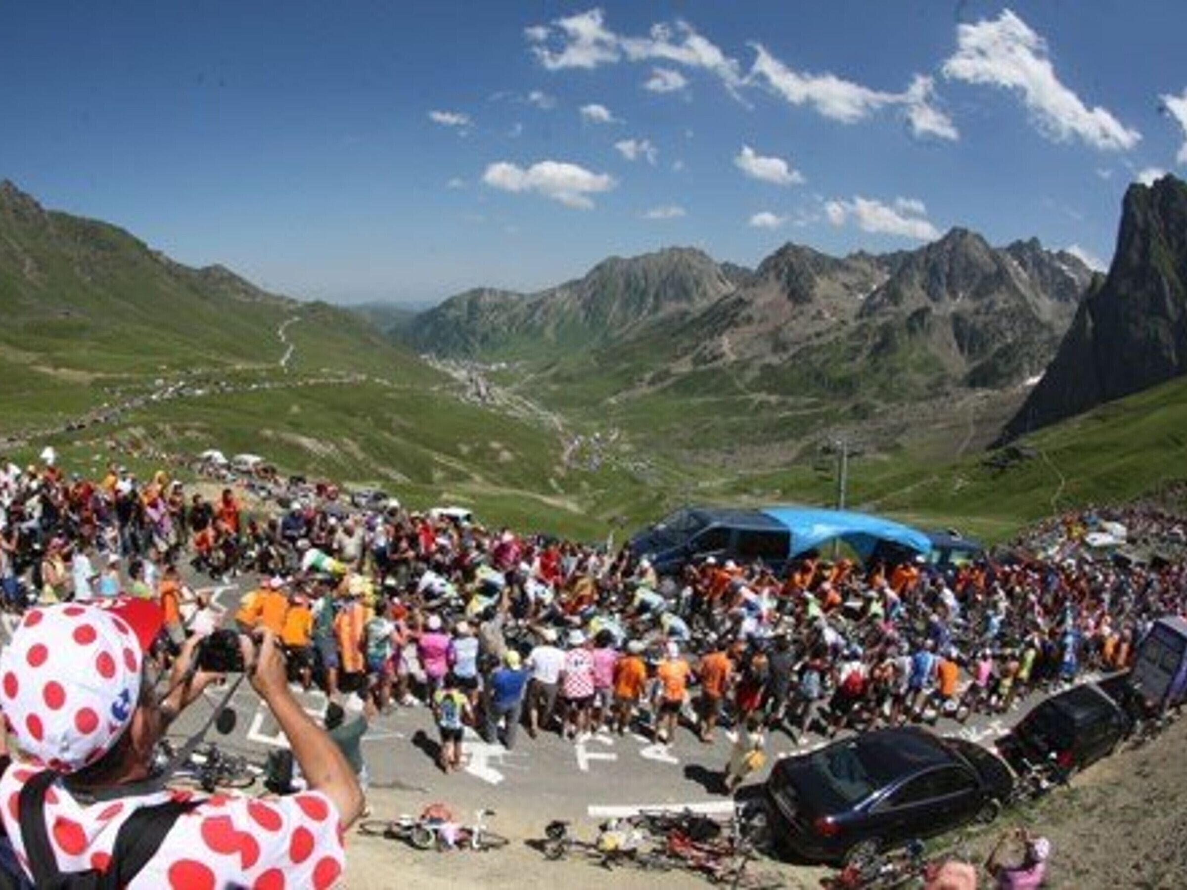 Un paisaje montañoso con una multitud de personas reunidas al frente.