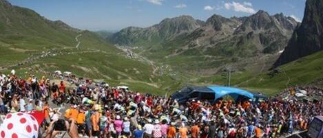 Un paisaje montañoso con una multitud de personas reunidas al frente.