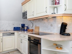 A modern kitchen with white cabinets, a built-in microwave, a coffee maker, and a toaster.