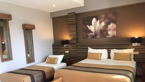 A hotel room with two beds, a large mirror, and a wall-mounted TV. - Hotel Colibri (Kone)