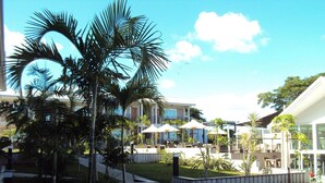 A resort with multiple buildings, outdoor seating areas, and palm trees. - Hotel Colibri (Kone)