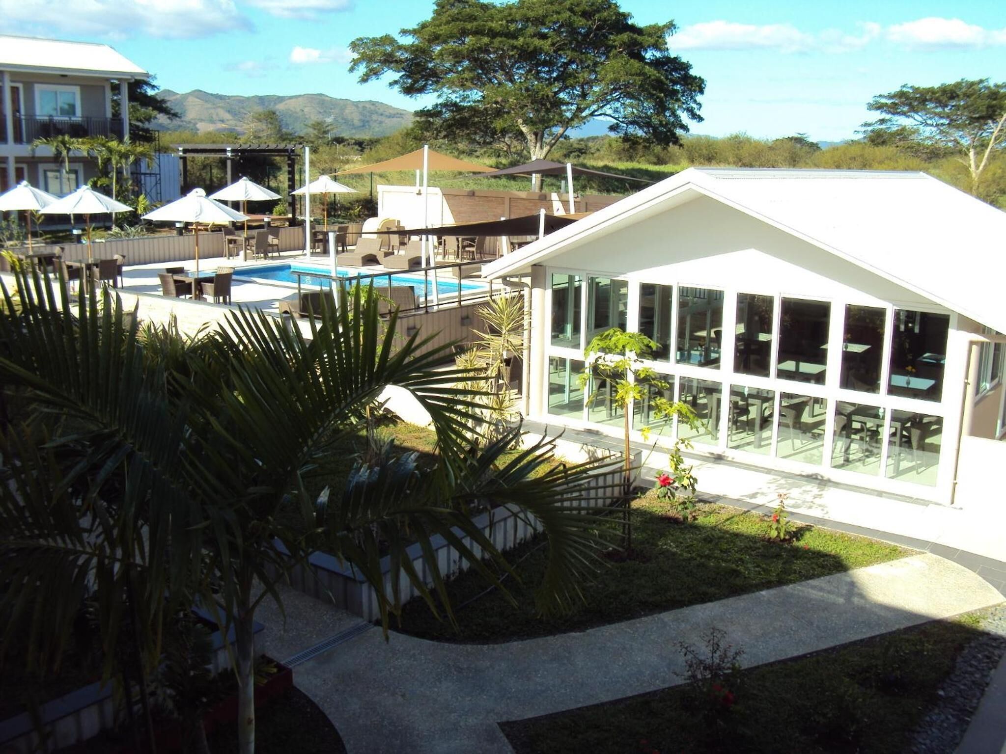 A resort with a pool, outdoor seating, and a building with large windows.