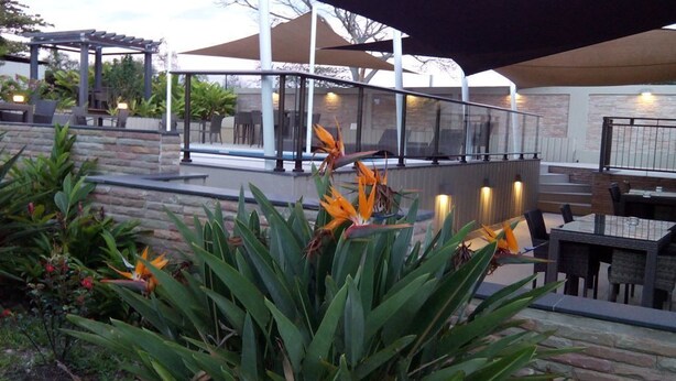 An outdoor patio area with stone steps, seating, and a pergola. - Hotel Colibri (Kone)