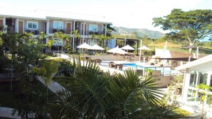 A hotel with a pool area, outdoor seating, and palm trees. - Hotel Colibri (Kone)