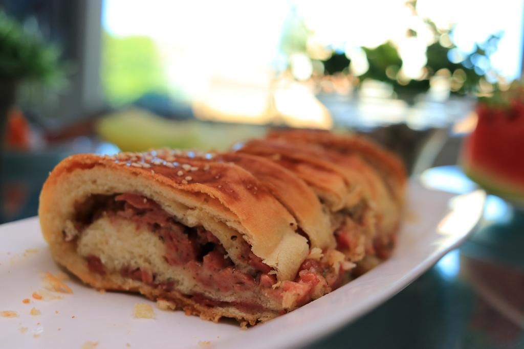A sandwich with a visible filling of meat and cheese, served on a white plate.