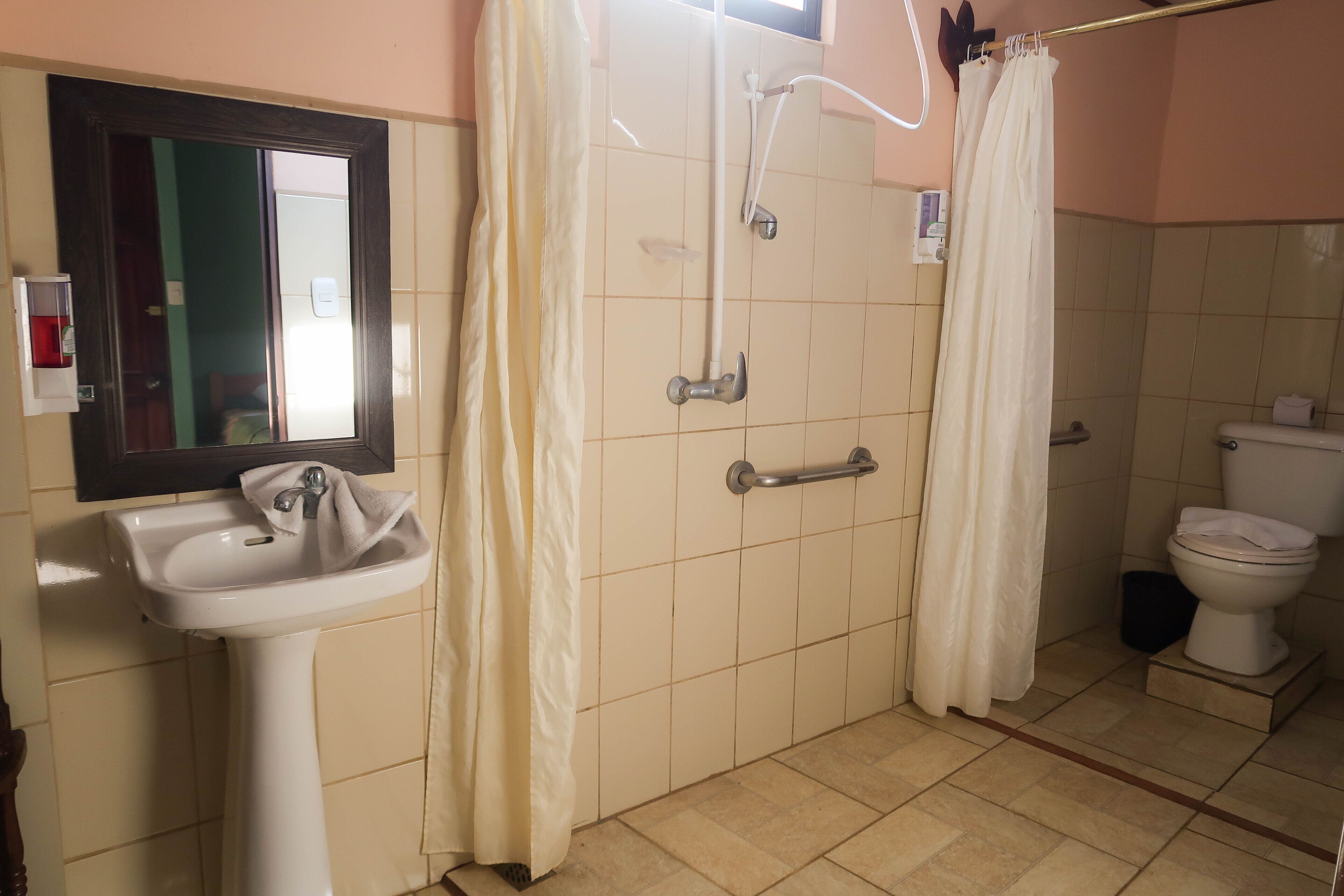 A bathroom with a sink, toilet, shower, and a mirror.