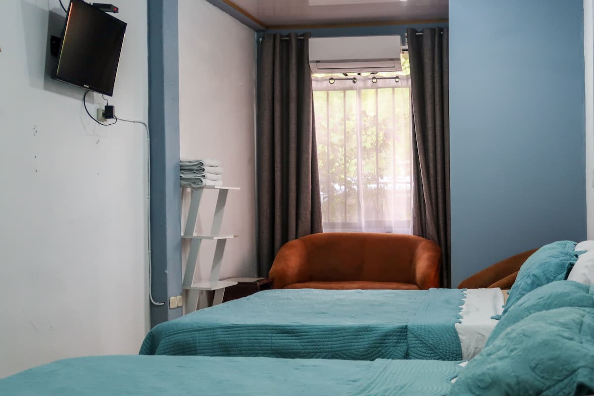 A small, compact room with a bed, a chair, and a TV mounted on the wall.
