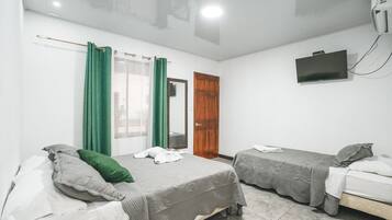 Une chambre avec deux lits, un téléviseur fixé au mur et une porte.