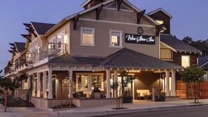 A two-story building with a sign reading "Wine Store Inn." It features a balcony on the upper floor and a covered outdoor seating area on the ground floor. - Wine Stone Inn (Santa Maria)