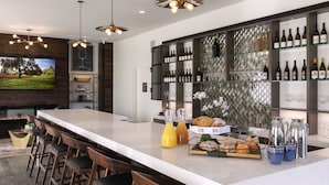A modern kitchen with a large island, bar stools, wine bottles, and a decorative backsplash. - Wine Stone Inn (Santa Maria)