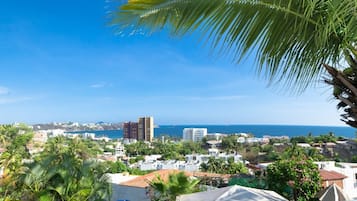 A coastal town with buildings, palm trees, and a view of the sea.