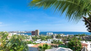 A coastal town with buildings, palm trees, and a view of the sea.