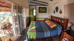 A bedroom with a bed, a ceiling fan, a window, and a door leading to a balcony. - Casa Artista BnB Manzanillo (Manzanillo)