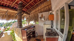 A kitchen with a gas stove, a sink, and a shelf with dishes. - Casa Artista BnB Manzanillo (Manzanillo)