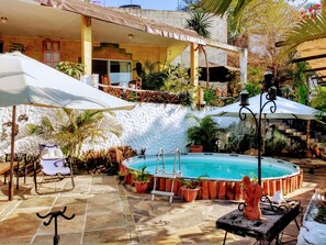 A pool area with a hot tub, lounge chairs, and potted plants.