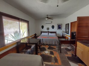 A bedroom with a bed, a desk, a chair, a ceiling fan, and a window with blinds.
