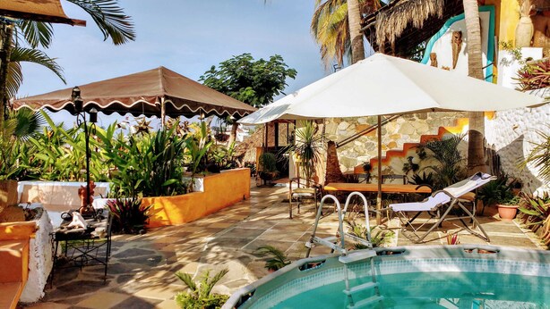 A pool area with a checkered floor, lounge chairs, and umbrellas. - Casa Artista BnB Manzanillo (Manzanillo)