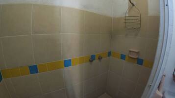 Un espacio de ducha pequeño con azulejos, un cabezal de ducha y un jabonera.