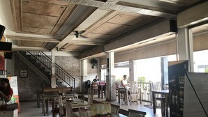 A spacious restaurant with exposed wooden beams, brick walls, and a mix of wooden and metal furniture. - Ons Canggu (Tibubeneng)