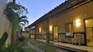 A hotel with a covered outdoor seating area, multiple rooms with doors, and a garden with plants and a pathway. - Ons Canggu (Tibubeneng)