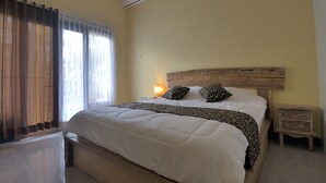 A bedroom with a bed, a nightstand, an air conditioning unit, and a window with curtains. - Ons Canggu (Tibubeneng)