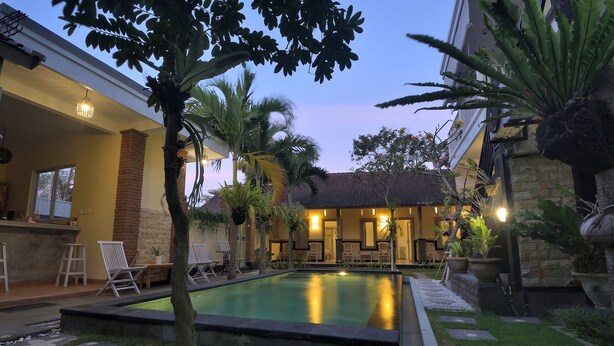 A pool area with a clear view of the pool, lounge chairs, and surrounding greenery. - Ons Canggu (Tibubeneng)