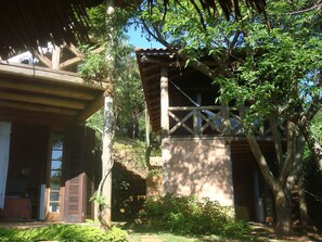A rustic wooden building with a balcony, surrounded by lush greenery and trees. - Pousada Villabella Villaggio (Florianópolis)